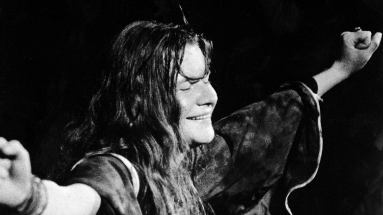 Janis Joplin sonriendo con los ojos cerrados en un escenario