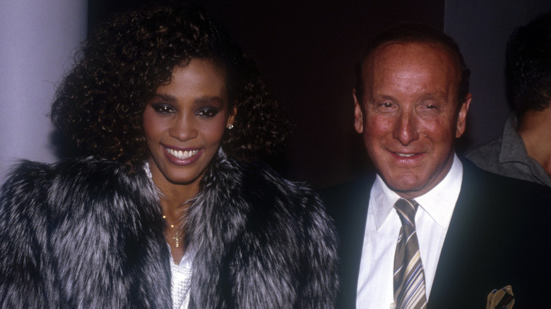Whitney Houston con abrigo de piel junto a Clive Davis