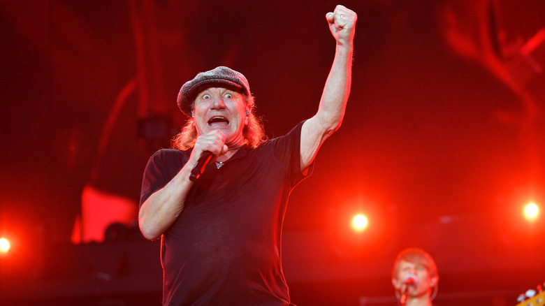 Brian Johnson con el puño en alto en un concierto en Wembley en 2024