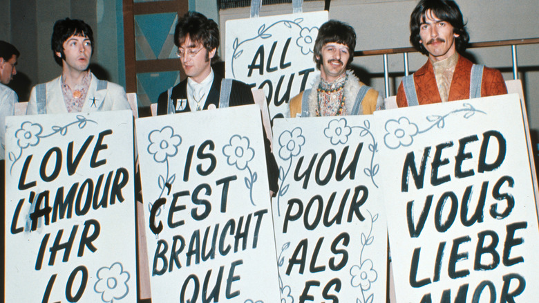 Los Beatles sosteniendo carteles en un evento de prensa
