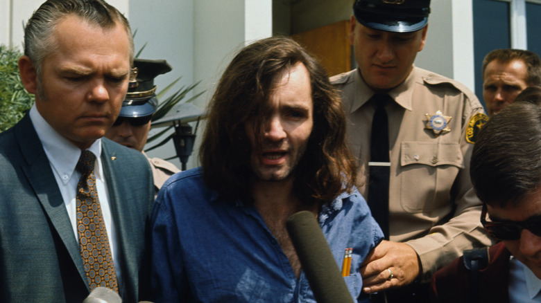 Charles Manson siendo entrevistado mientras sale de la corte con la policía