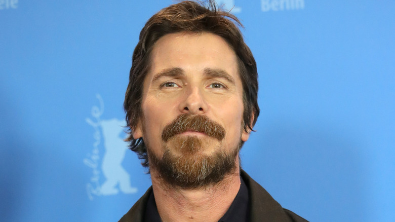 Christian Bale con barba en un fondo azul