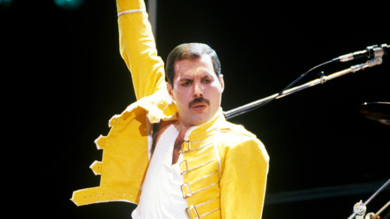 Freddie Mercury en escenario con brazo en alto