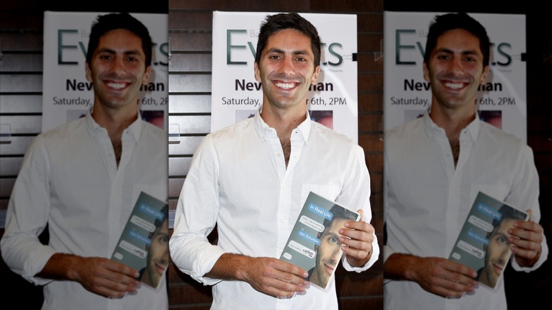 Nev Schulman posando con una copia de su libro