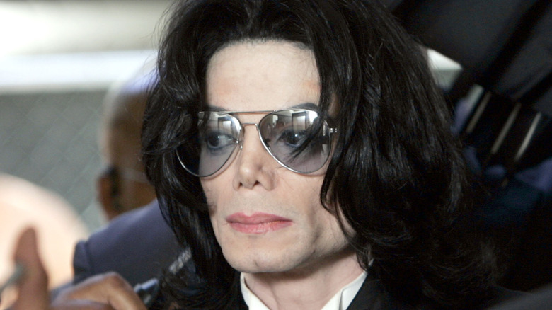 Michael Jackson con gafas y expresión seria en medio de una multitud