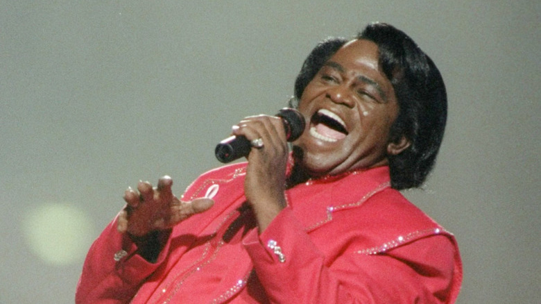 James Brown cantando en el escenario con traje rojo