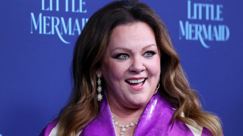 Melissa McCarthy sonriendo con vestido morado