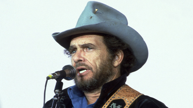 Merle Haggard con sombrero de cowboy cantando en escenario