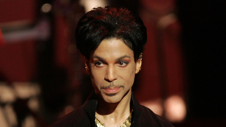 Prince en escenario con sonrisa y mirada distraída