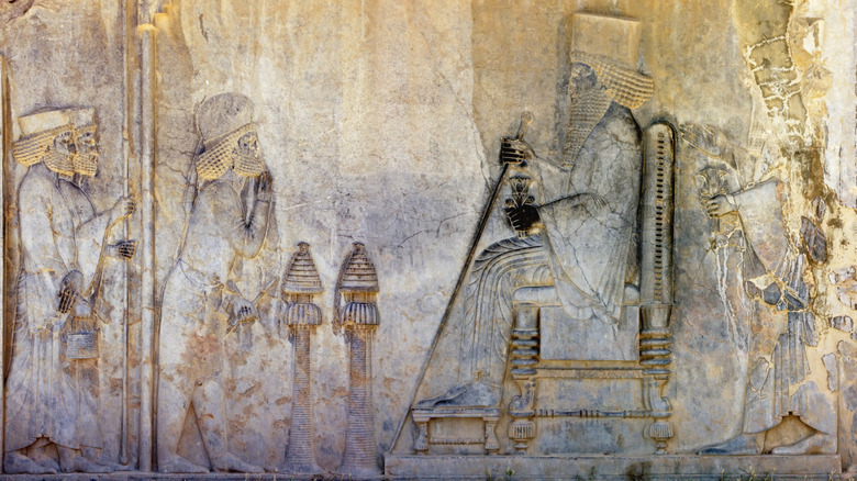 Relieve de piedra de la era mesopotámica con personas ante un rey en un trono
