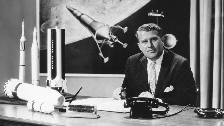 Wernher von Braun sentado en un escritorio con modelos de cohetes de la NASA