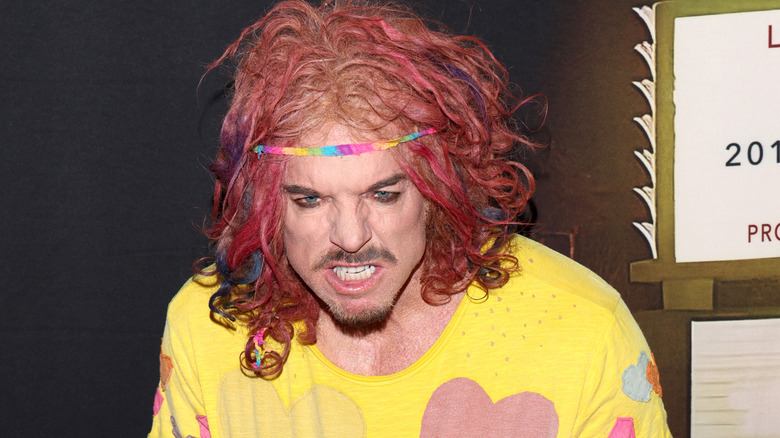 Carrot Top con visible expresión de molestia y usando una diadema arcoíris