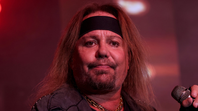 Vince Neil con micrófono en mano y expresión triste