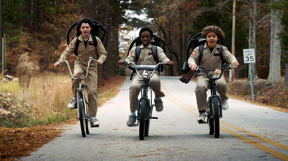 Los niños montando en bicicleta con disfraces de Cazafantasmas