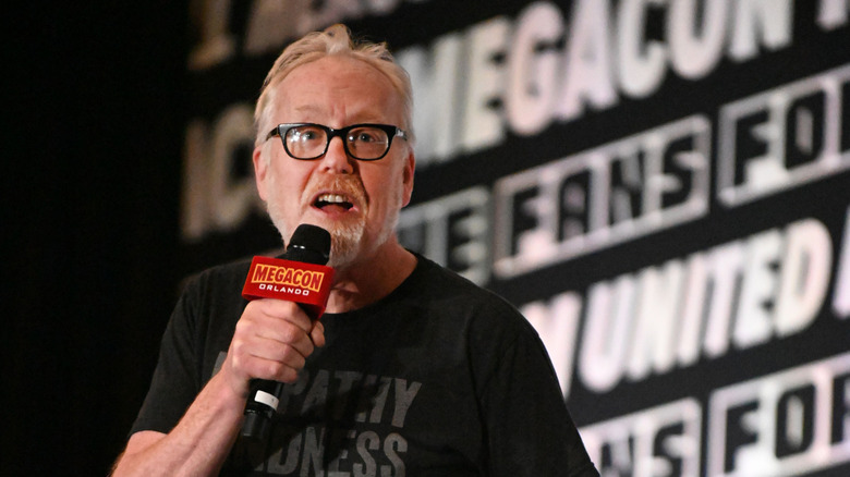 Adam Savage hablando frente a una pared de palabras