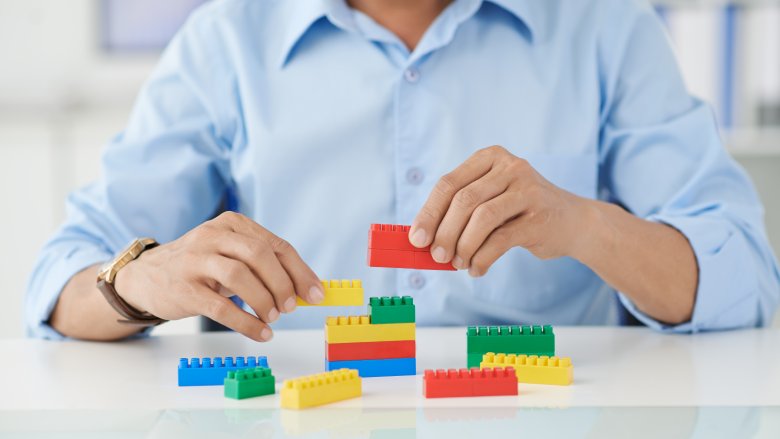 Persona en camiseta azul en mesa blanca jugando con Lego