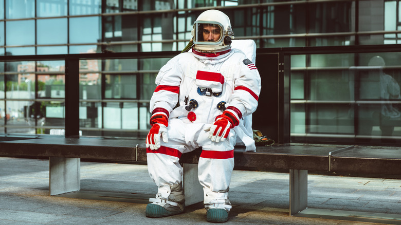 Astronauta esperando en una parada de autobús